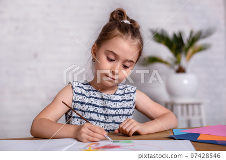Inspired little girl at the table draw with paints Inspired little girl at the table draw with paints 97428546