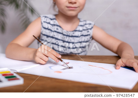 Inspired little girl at the table draw with paints. Close-up Inspired little girl at the table draw with paints. Close-up 97428547