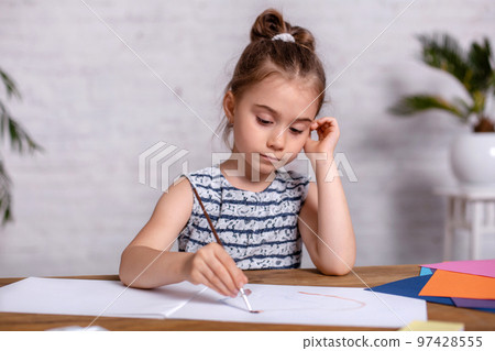 Inspired little girl at the table draw with paints Inspired little girl at the table draw with paints 97428555
