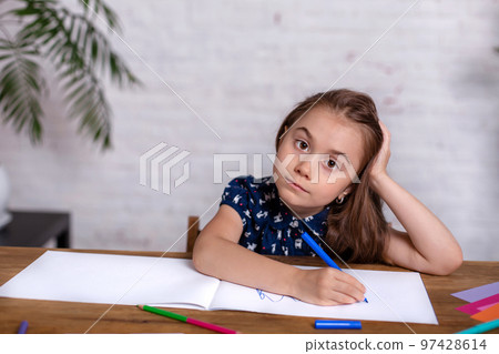 Inspired little girl at the table draw with crayons or do home work Inspired little girl at the table draw with crayons or do home work 97428614