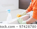 Middle-aged man cleaning the bathtub in the bathroom 97428780
