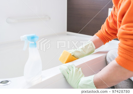 Middle-aged man cleaning the bathtub in the bathroom Middle-aged man cleaning the bathtub in the bathroom 97428780