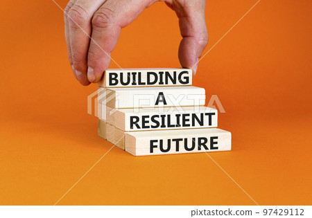 Building a resilient future symbol. Concept word Building a resilient future on wooden blocks. Beautiful orange table orange background. Business and building a resilient future concept. Copy space. 97429112