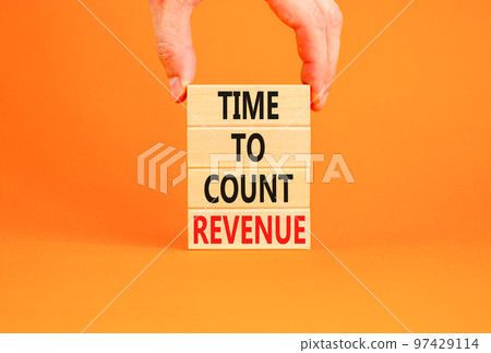 Time to count revenue symbol. Concept word Time to count revenue on wooden blocks. Businessman hand. Beautiful orange table orange background. Business and time to count revenue concept. Copy space. Time to count revenue symbol. Concept word Time to count revenue on wooden blocks. Businessman hand. Beautiful orange table orange background. Business and time to count revenue concept. Copy space. 97429114