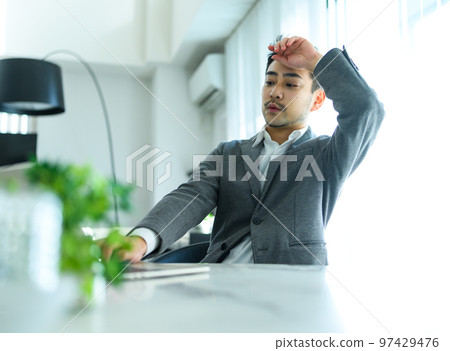 A man in his thirties working from home is tired 97429476