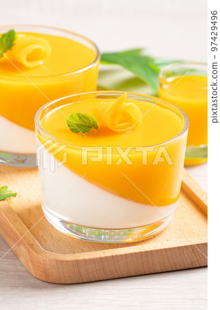 Delicious double colored mango panna cotta mousse pudding on wooden table background. 97429496