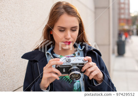 Portrait of a pretty young tourist taking photographs with vintage retro camera 97429552