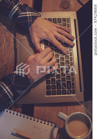 Young man drinking coffee in cafe and using laptop. Man's hands Young man drinking coffee in cafe and using laptop. Man's hands 97429669