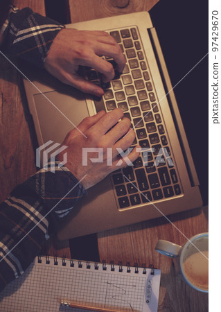 Young man drinking coffee in cafe and using laptop. Man's hands Young man drinking coffee in cafe and using laptop. Man's hands 97429670