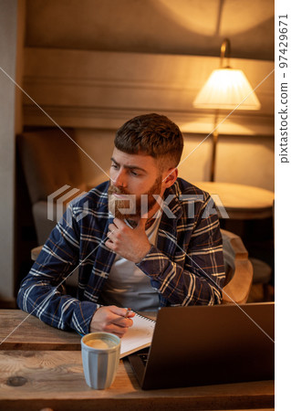 Casual business man or freelancer planning his work on notebook, working on laptop computer with smart phone, cup of coffee on table at coffee shop or home office. Casual business man or freelancer planning his work on notebook, working on laptop computer with smart phone, cup of coffee on table at coffee shop or home office. 97429671