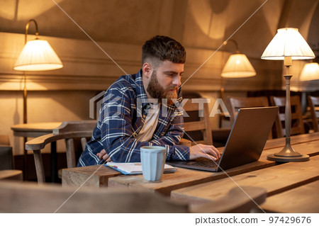 Young professional surfing the Internet on his laptop in a cafe 97429676