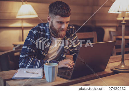 Young professional surfing the Internet on his laptop in a cafe 97429682
