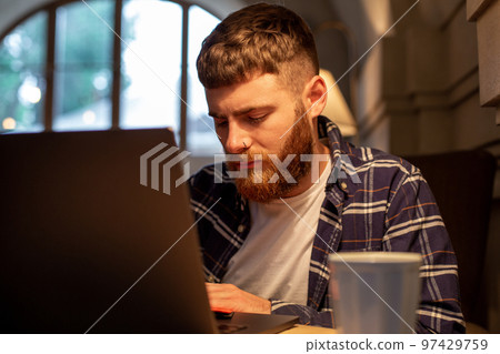 Young professional surfing the Internet on his laptop in a cafe 97429759
