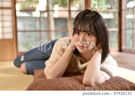 A young smiling woman relaxing in a Japanese-style room in an old folk house 97430135