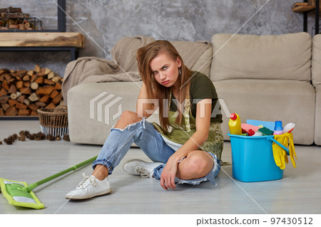Woman housewife feel tired sitting on floor at living room after cleaning at home. 97430512