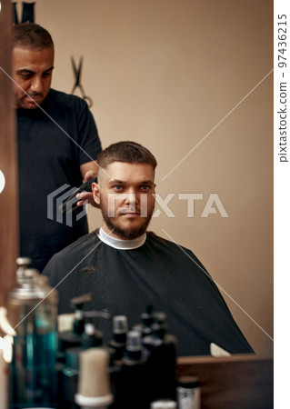 Barber shaving caucasian man in barber shop Barber shaving caucasian man in barber shop 97436215
