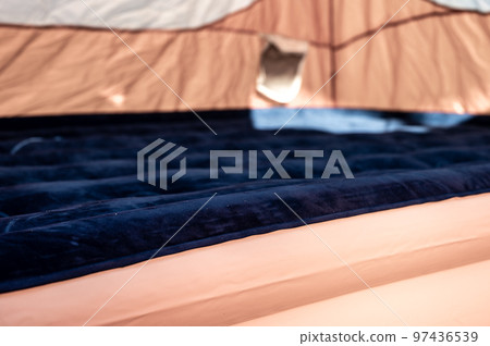 Selective focus of an inflatable air mattress on the floor of a tent being filled up.  97436539