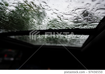 Inside a vehicle looking up to a sunroof with water droplets Inside a vehicle looking up to a sunroof with water droplets 97436550