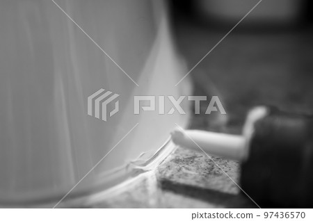 Selective focus on silicone caulking ready to be applied around the seal of a bathroom toilet. Selective focus on silicone caulking ready to be applied around the seal of a bathroom toilet. 97436570