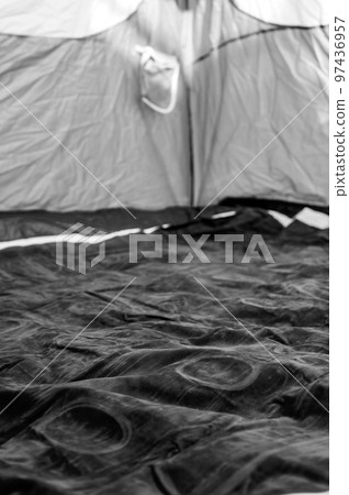 Selective focus of an inflatable air mattress on the floor of a tent being filled up.  Selective focus of an inflatable air mattress on the floor of a tent being filled up.  97436957