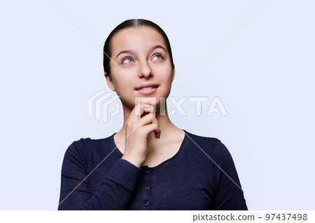 Pensive teenage female dreamily looking away, white studio background 97437498