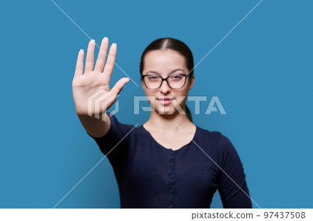 Serious confident teenage girl looking at camera making stop gesture with palm Serious confident teenage girl looking at camera making stop gesture with palm 97437508