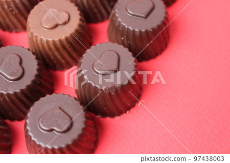 chocolate case candies with the symbol of the heart. Valentine's Day of Chocolate Sweets. Candy bonbon on a red background with space for copyspace text 97438003