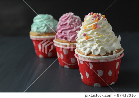 three cupcakes white green pink with sprinkles on a black background. Holiday anniversary greetings three cupcakes white green pink with sprinkles on a black background. Holiday anniversary greetings 97438010