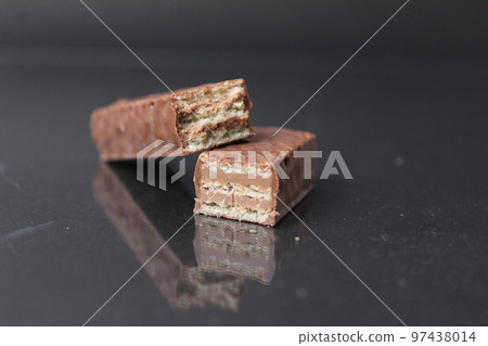 chocolate candy from waffle sheets and chocolate filling praline ganache. Bar cake in chocolate glaze on a black background. Chocolate Sweets Day chocolate candy from waffle sheets and chocolate filling praline ganache. Bar cake in chocolate glaze on a black background. Chocolate Sweets Day 97438014