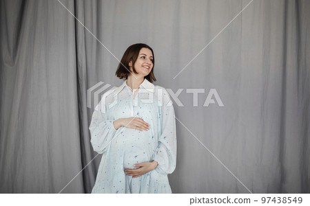 Attractive pregnant woman in blue dress on gray background 97438549