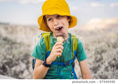Boy tourist boy eating turkish ice cream while exploring valley with rock formations and fairy caves near Goreme in Cappadocia Turkey 97440490