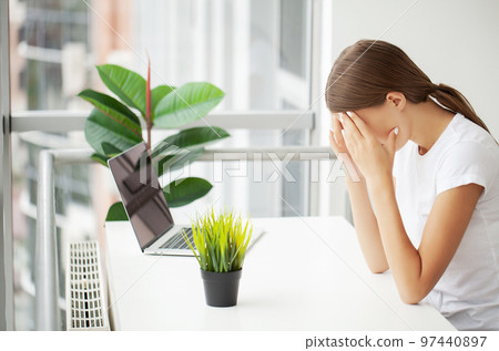 Stressed young office worker holding head because of pain in office 97440897