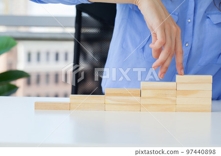 Woman hand stepping up wood block stacking as step stair Woman hand stepping up wood block stacking as step stair 97440898