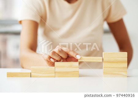 Woman hand arranging wood cube stacking as stair step shape Woman hand arranging wood cube stacking as stair step shape 97440916