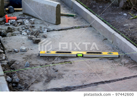 Defocus level tool. Construction industry. Yellow level tool spirit and green fishing line. Bricklayer and paving master. Pavement tools outside. Out of focus 97442600