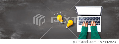 Person using a laptop computer and light bulbs Person using a laptop computer and light bulbs 97442623