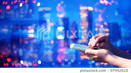 Person using a smart phone on a blurred city background Person using a smart phone on a blurred city background 97442628