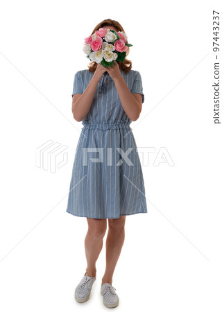 Full-length portrait of caucasian woman in blue dress hiding behind the bouquet of flowers isolated over white background 97443237
