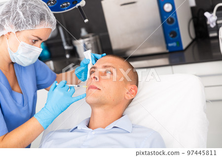 Man receiving facial contouring injections in cosmetology clinic 97445811