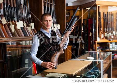 Portrait of an arms shop salesman with an air gun in hands Portrait of an arms shop salesman with an air gun in hands 97445896