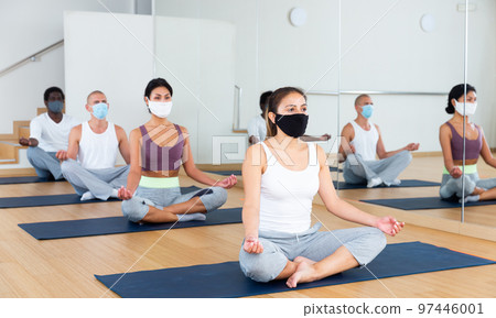 Group of people in protective masks practicing yoga poses Group of people in protective masks practicing yoga poses 97446001