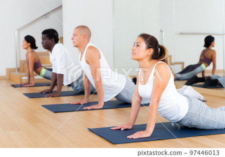 Young women and men exercising Hatha yoga poses in studio 97446013