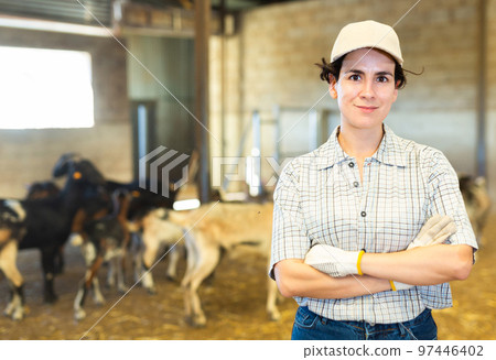 Happy Latin female farmer with crossed hands on chest on goat cattle farm 97446402