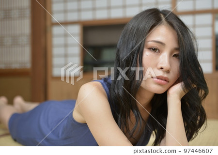 A beautiful young woman wearing a dress relaxing in a Japanese-style room in an old private house 97446607