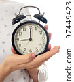 Woman hands holding black alarm clock 97449423