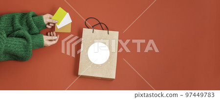 Xmas shopping concept. Woman's hands holding a gift bag and a credit card on a red background, Xmas shopping concept. Woman's hands holding a gift bag and a credit card on a red background, 97449783