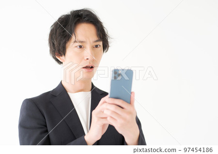 Men in their 20s looking at a smartphone Men in their 20s looking at a smartphone 97454186