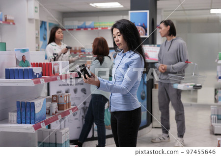 Elderly client looking at bottles of pills to buy prescription treatment from pharmacy shelves, pharmaceutical supplies. Asian woman examining medical products in packages to cure disease. 97455646