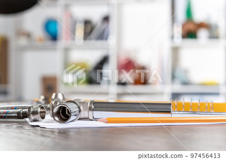 Flexible steel water hoses laying on table 97456413