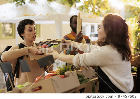 From farm to doorstep delivery concept. Young woman carrying delivery bag and picking up order at food market, delivering healthy fresh organic produce in box from local farming. 97457602